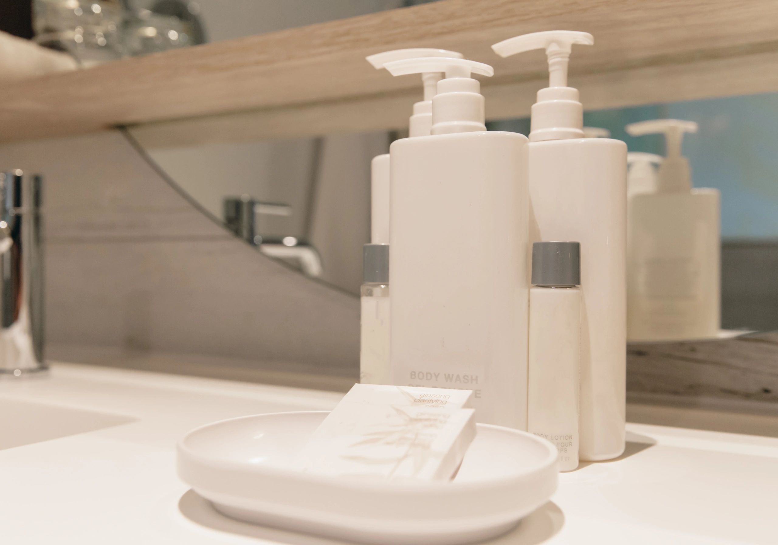 Bathroom vanity with white toiletries and soap dispensers